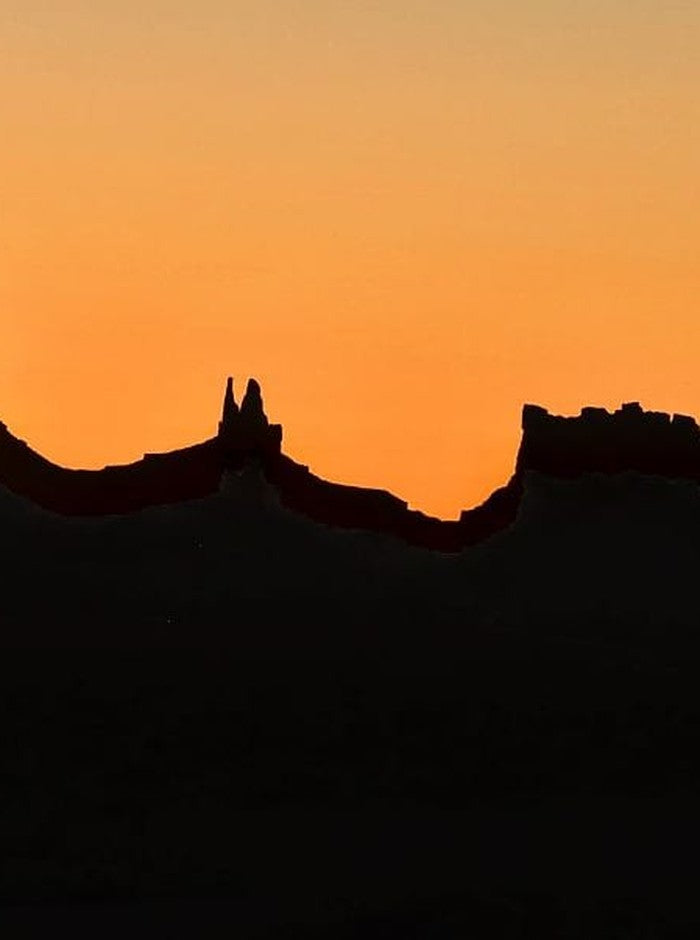 Monument Valley at dawn, silhouetted against a burning orange sky